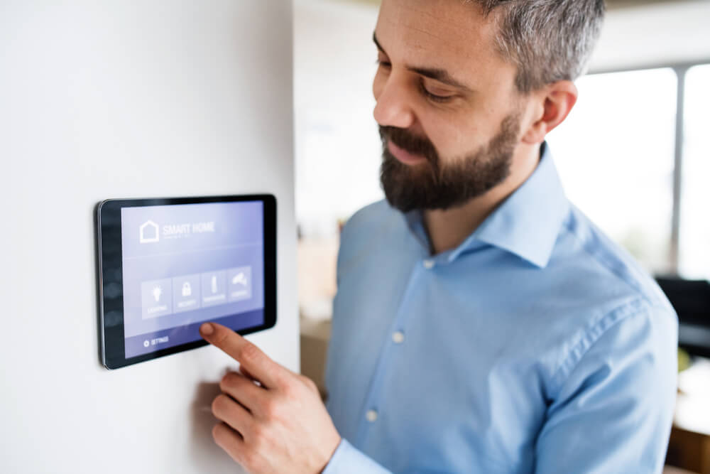 A man pointing to a tablet with smart home screen at home